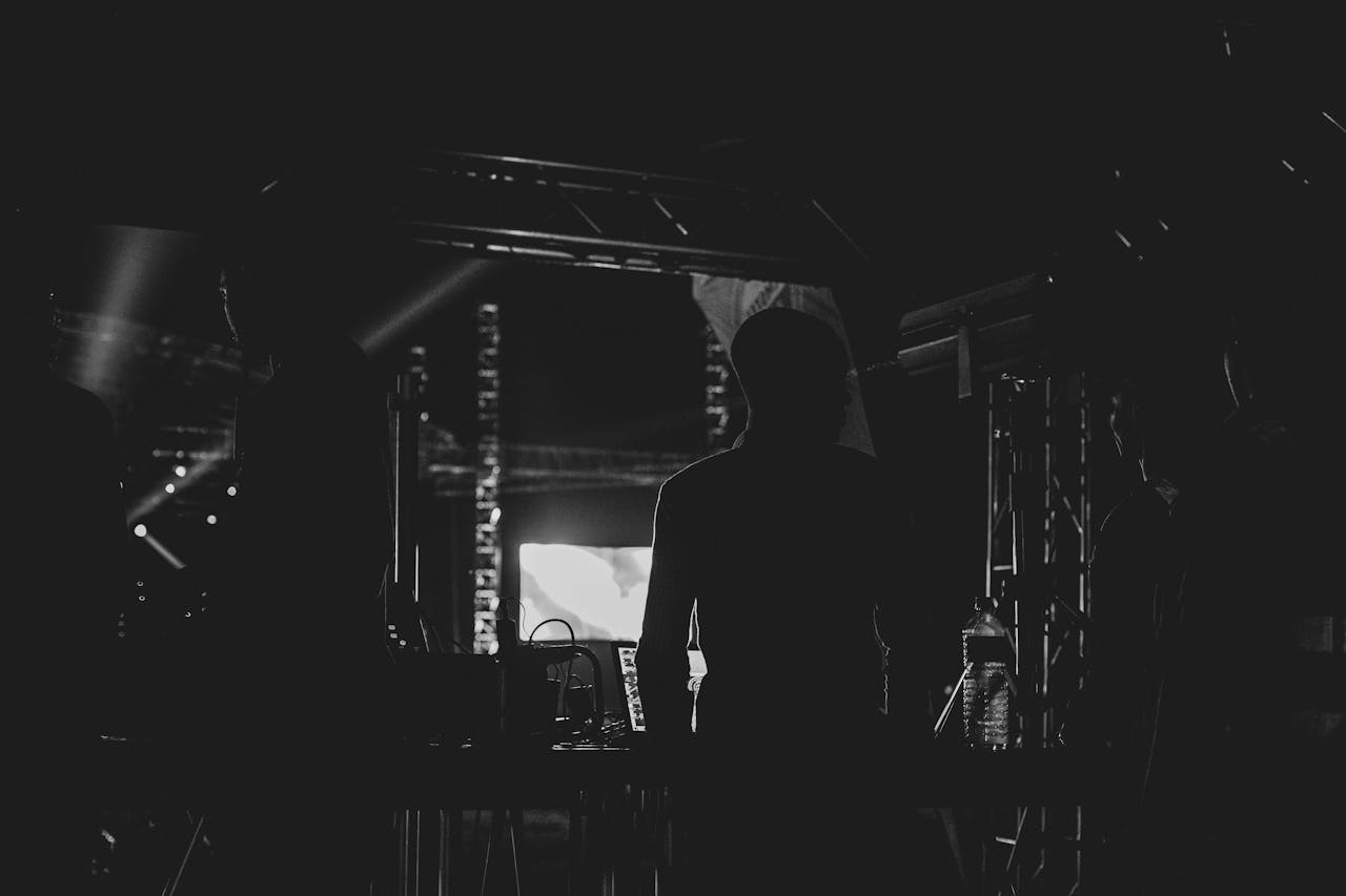 Home Silhouetted crew standing backstage at a concert, focusing on silhouette effect.
